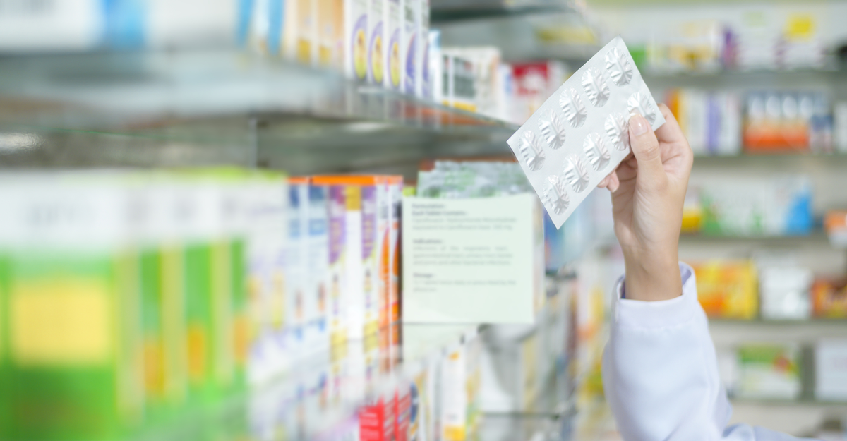 A Female pharmacist wearing lab coat in a modern pharmacy drugstore., selecting a medicine for customer.
