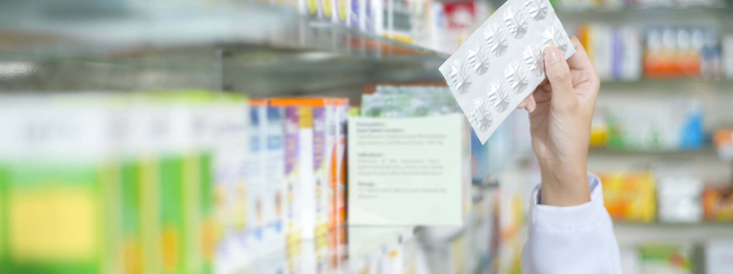 A Female pharmacist wearing lab coat in a modern pharmacy drugstore., selecting a medicine for customer.
