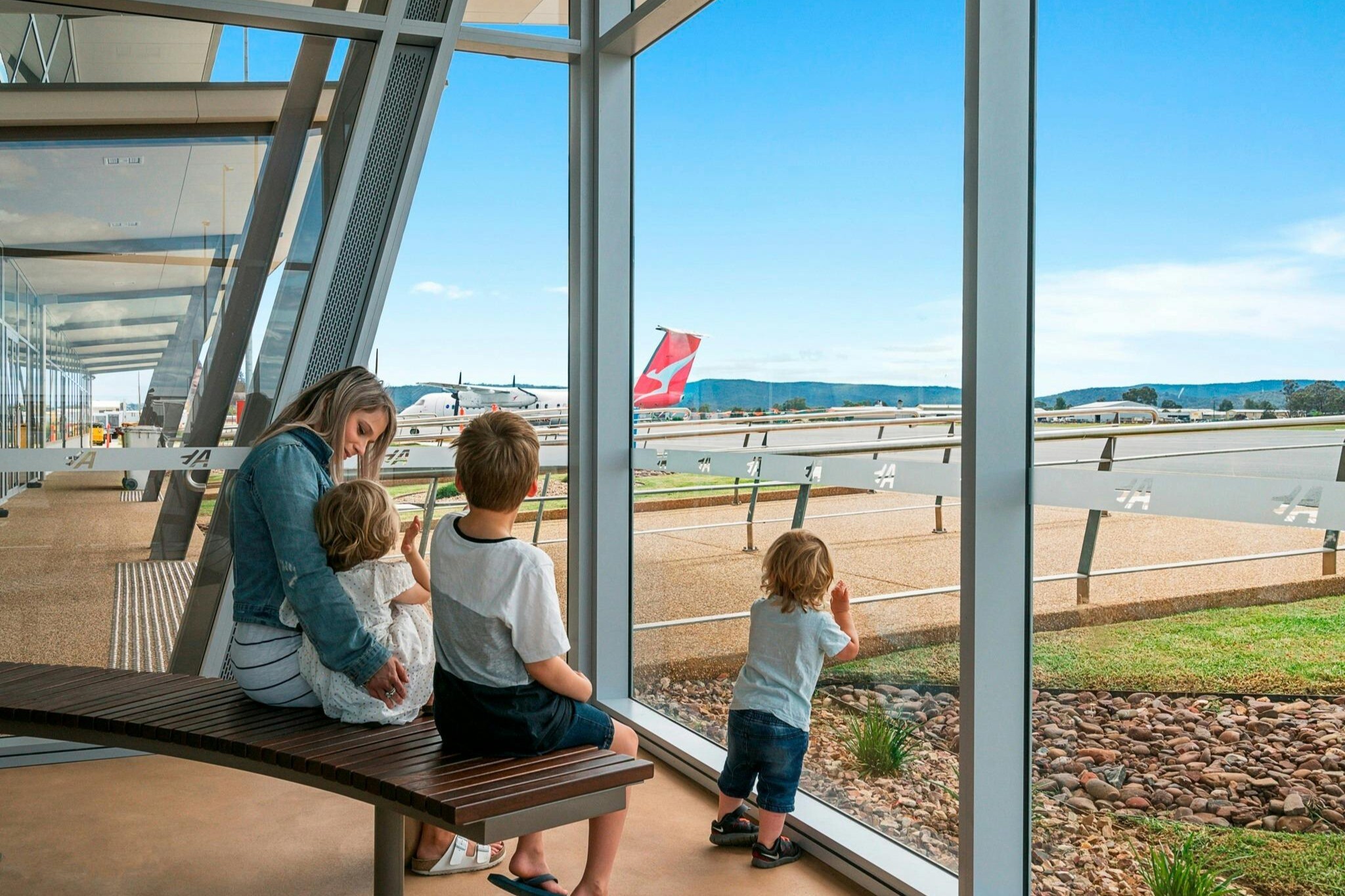 A family watching planes through the terminal windows at Albury Airport.