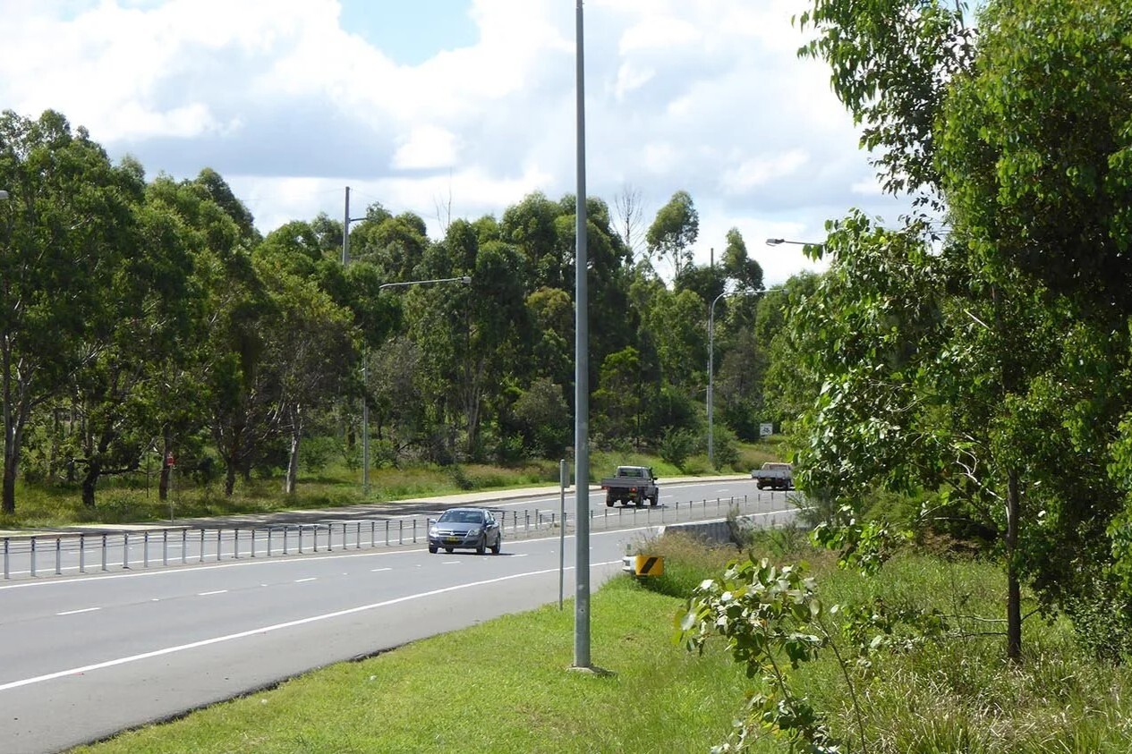 Vehicles travelling along Camden Valley Way surrounded by bushland.