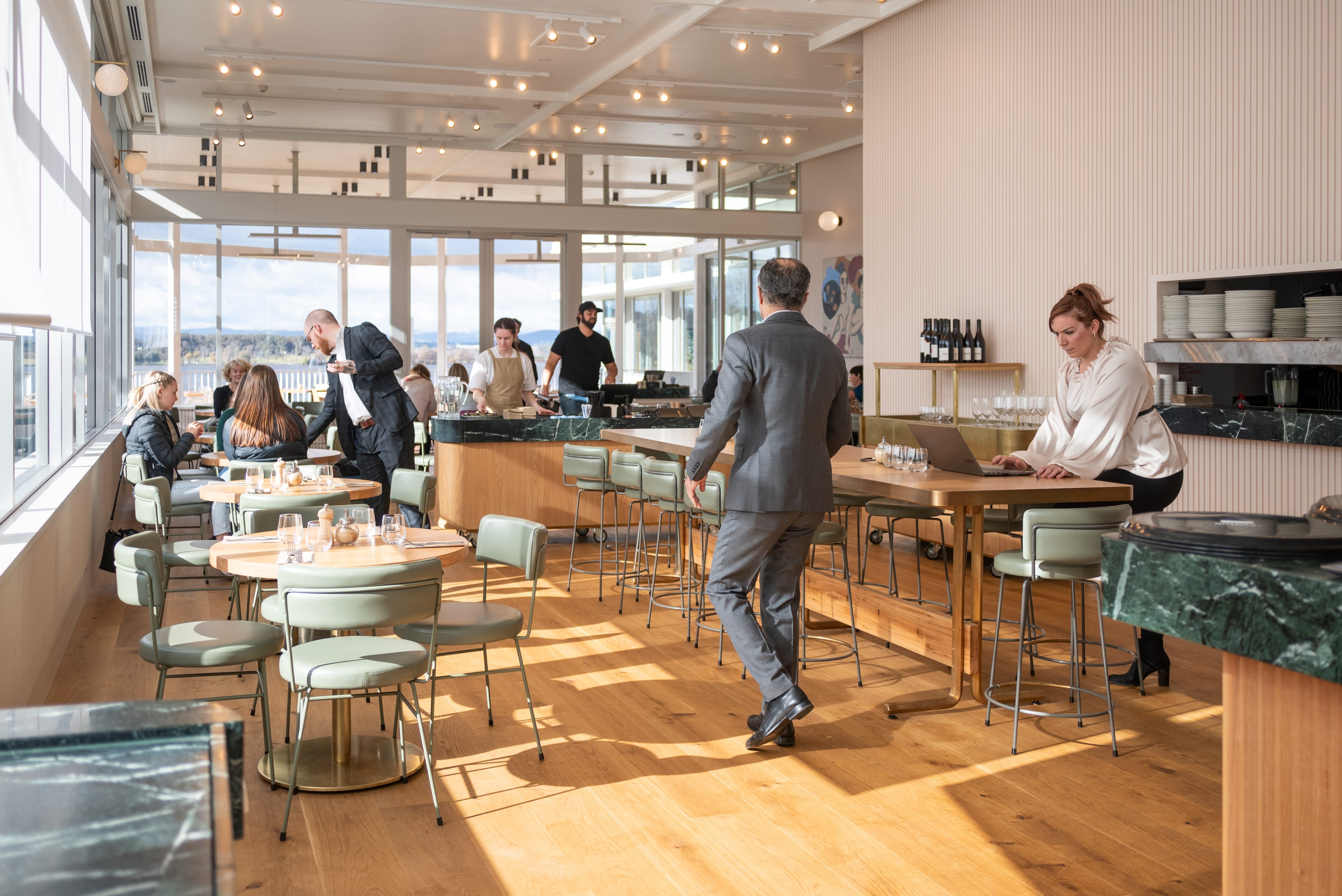 The interior of a bustling cafe in Parkes, Canberra, is bathed in the gentle morning sunlight, casting warm hues across the room.
