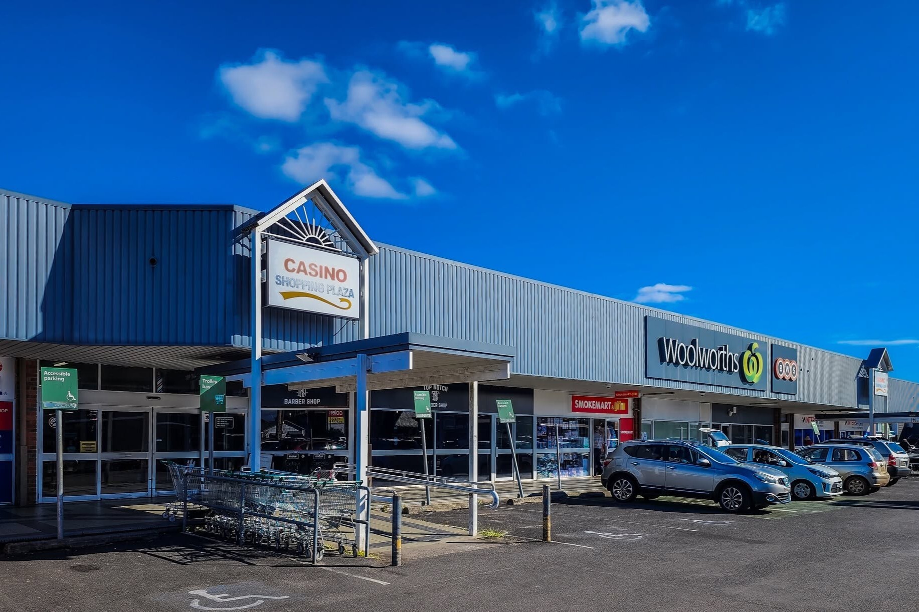 Exterior of Casino Shopping Plaza with Woolworths and parked cars.