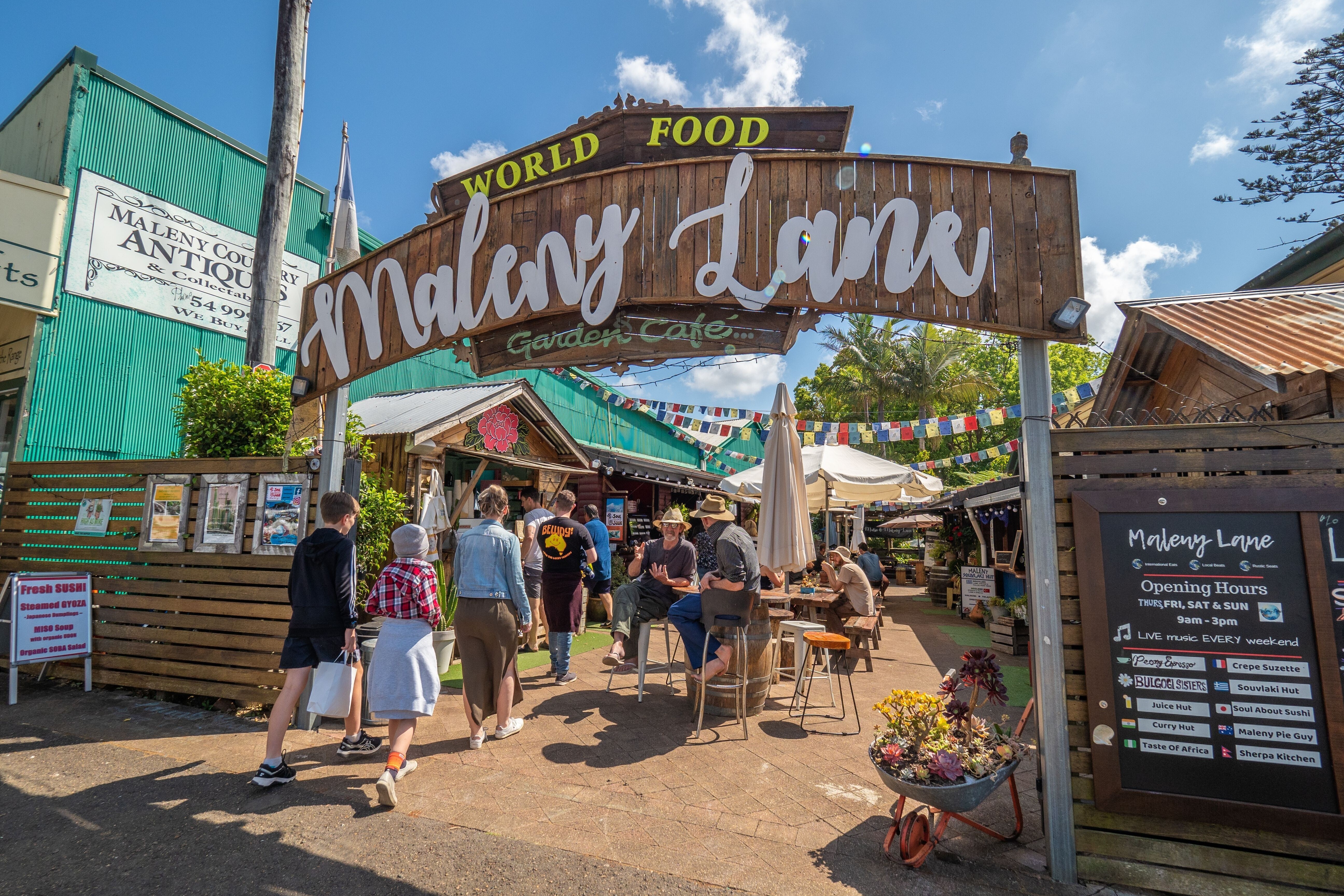 People sitting and walking through Maleny Lane, home to colourful cafes and shops in Maleny
