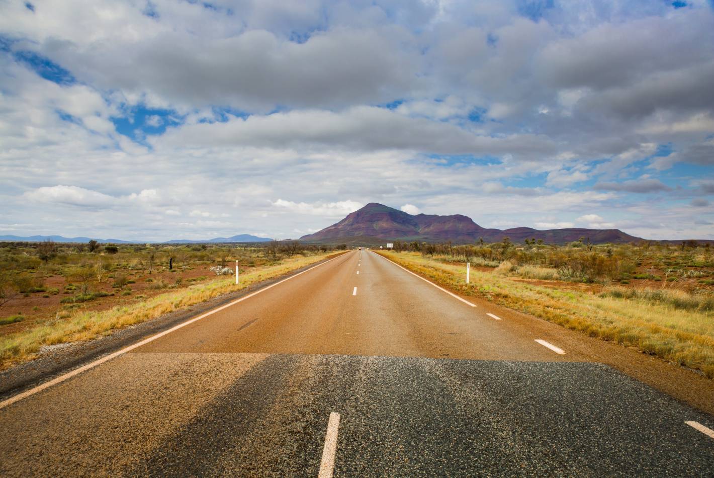 **Alt text:** Bruce Highway stretching through the outback towards distant mountains.