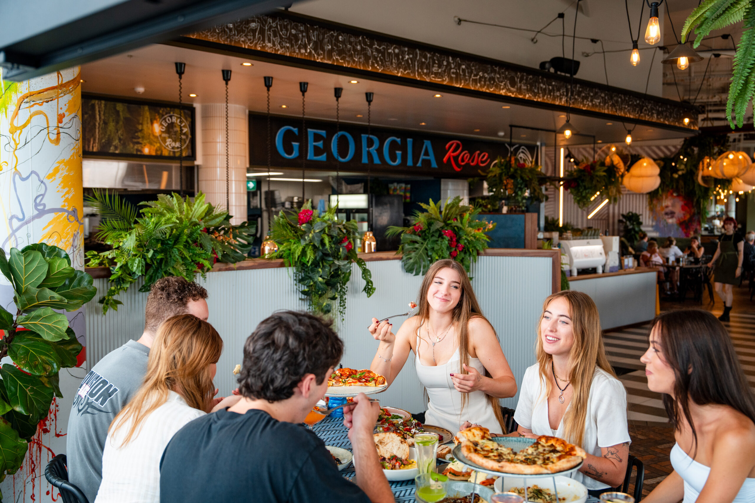 Friends sharing pizzas and drinks at Georgia Rose in Shell Cove.