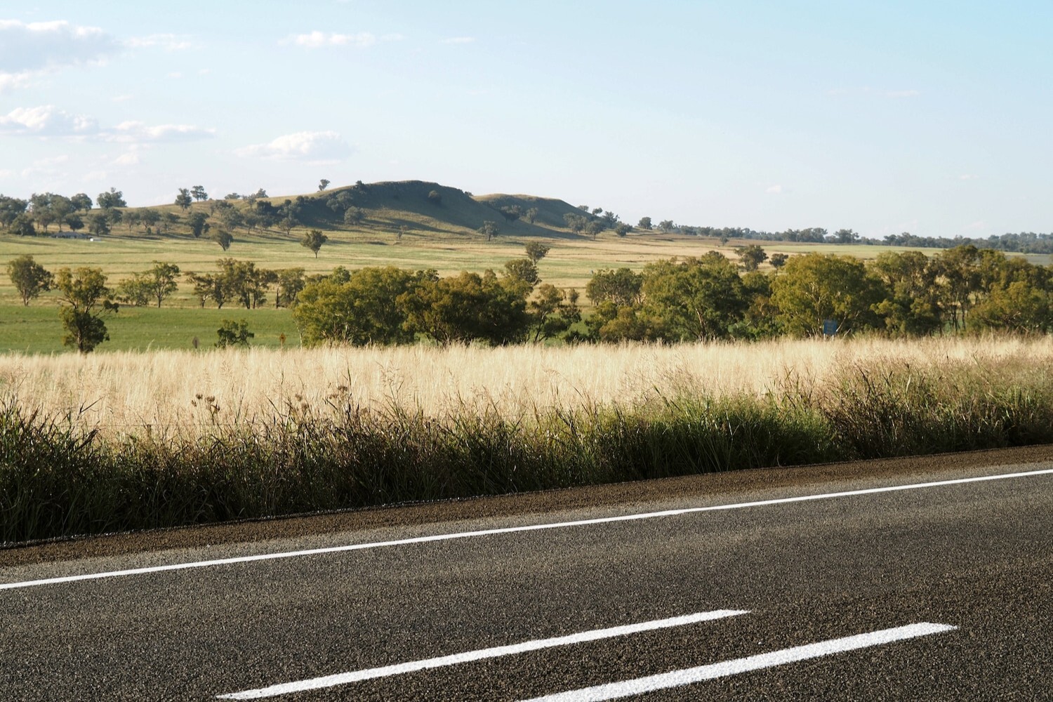 New England Highway passing through open countryside with rolling hills.